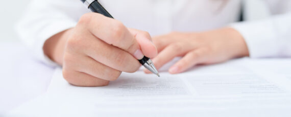 Business Women Filling Contract At Desk.